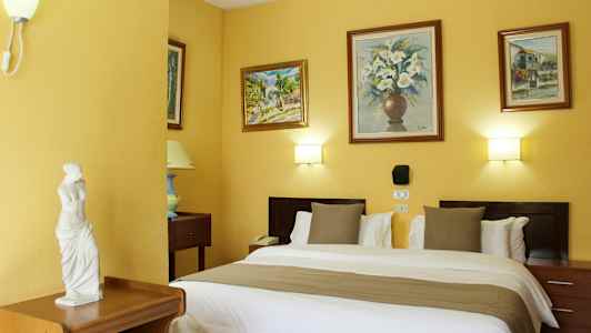 Ett hotellrum med en dubbelsäng, dekorerade väggar med målningar och en liten staty på en möbel. (AI-genererad text)