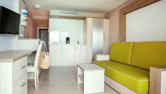 Modernt hotellrum med soffa, skrivbord och pentry. (AI-genererad text)