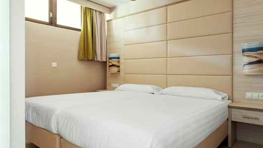 Ett hotellrum med två sängar och en beige väggpanel. (AI-genererad text)