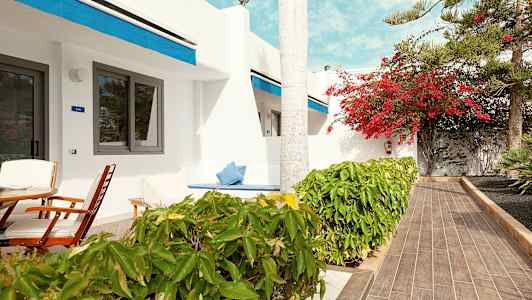 Terrass med sittmöbler framför en vit byggnad med blå detaljer. (AI-genererad text)