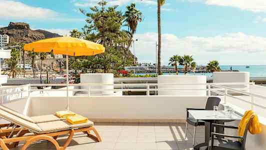 Solstolar och bord med utsikt över havet och palmer. (AI-genererad text)