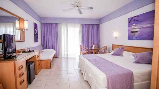 Hotellrum med en stor säng, en enkelsäng, ett bord med stolar och en TV-bänk. (AI-genererad text)