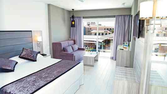 Hotellrum med säng, soffa, och balkongutsikt. (AI-genererad text)