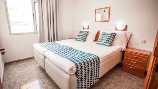 Dubbelrum med två enkelsängar, sängbord och fönster. (AI-genererad text)