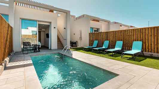 Charmig pool framför en vit modern byggnad, omgivet av solstolar. (AI-genererad text)