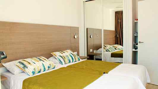 Dubbelrum med två enkelsängar, en spegel och inredning i trä. (AI-genererad text)