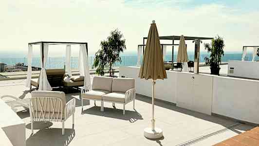 En terrass med solstolar, parasoll och utsikt över havet. (AI-genererad text)