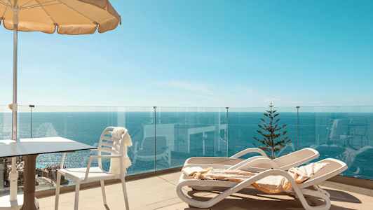 Terrass med solstolar, parasoll och havsutsikt. (AI-genererad text)