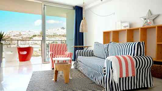 Ett vardagsrum med en soffgrupp framför en glasdörr som leder till en balkong. (AI-genererad text)