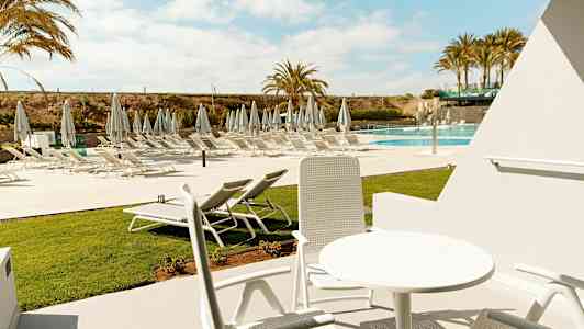 Utemöbler i solig miljö med utsikt över solstolar vid poolen. (AI-genererad text)