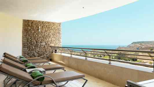 Terrass med solsängar framför havsutsikt. (AI-genererad text)