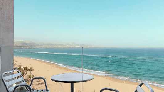 Utsikt från en balkong mot en sandstrand och hav. (AI-genererad text)