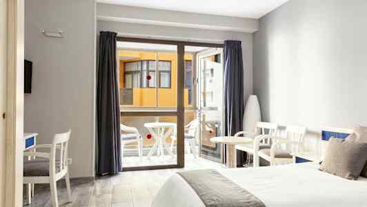 Hotellrum med två sängar, sittmöbler och en balkong i bakgrunden. (AI-genererad text)