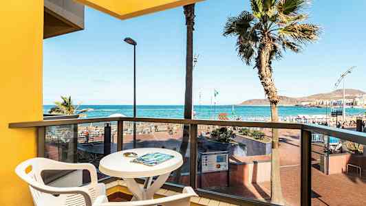 Utsikt från en balkong med bord och stolar mot havet och stranden. (AI-genererad text)