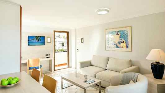 Ljus vardagsrum med soffa, fåtölj, soffbord och en dekorerad tavla ovanför soffan. (AI-genererad text)