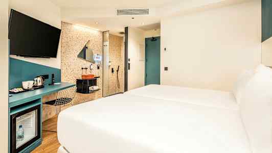 Hotellrum med säng, skrivbord och badrumsområde. (AI-genererad text)