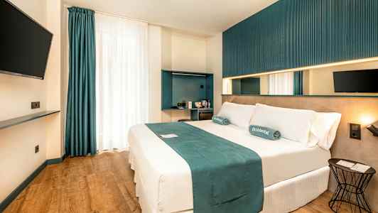 En modern hotellrum med en dubbelsäng, väggmonterad TV och minimalistisk inredning. (AI-genererad text)