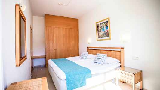 Hotellrum med en dubbelsäng, trädetaljer och en garderob. (AI-genererad text)