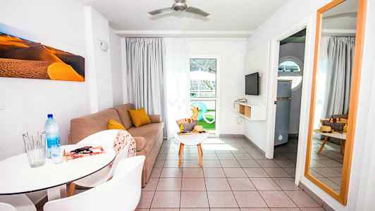 Ett vardagsrum med en soffa, ett avlastningsbord, en spegel och ett matbord med stolar. (AI-genererad text)