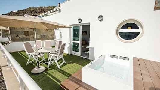 Terrass med stolar, bord och en mindre pool. (AI-genererad text)