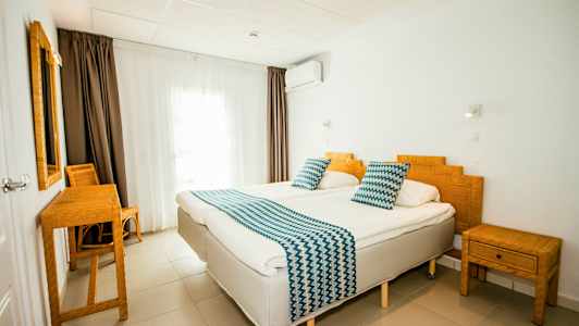 Ett hotellrum med två enkelsängar, bambumöbler och vita väggar. (AI-genererad text)