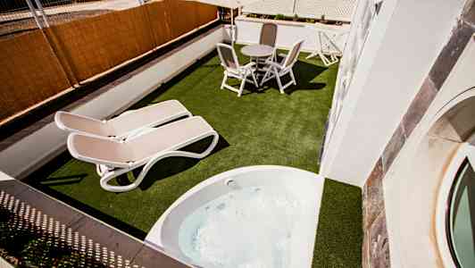 En terrass med bord, stolar, två solstolar och en bubbelpool. (AI-genererad text)