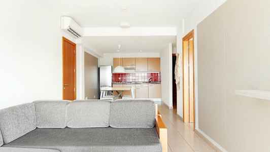 Bild av ett ljust vardagsrum med en grå soffa i förgrunden och ett kök i bakgrunden. (AI-genererad text)