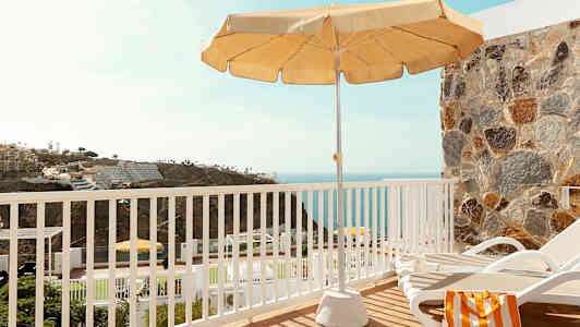 Utsikt från en terrass med en solstol, parasoll och hav i bakgrunden. (AI-genererad text)