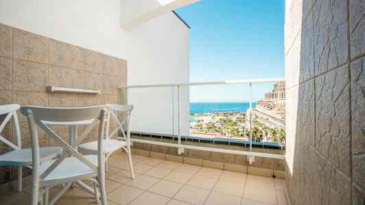 Hotellbalkong med två stolar och bord, med utsikt över havet. (AI-genererad text)