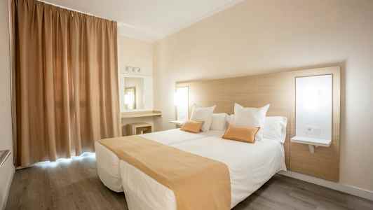 Hotellrum med två enkelsängar, beige och vitt färgschema. (AI-genererad text)