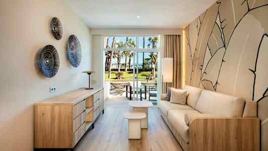 Ett modernt inrett vardagsrum med trädetaljer och en beige soffa, utsikt mot en grön trädgård genom glasdörrar. (AI-genererad text)