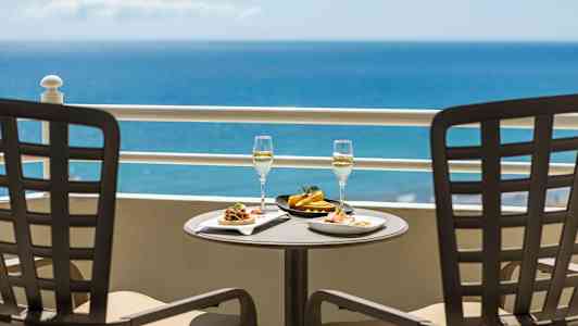 Två tallrikar med mat och två glas med dryck på ett bord med havsutsikt. (AI-genererad text)