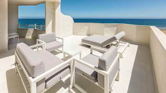 Takterrass med vitmålad inredning och utsikt över havet. (AI-genererad text)