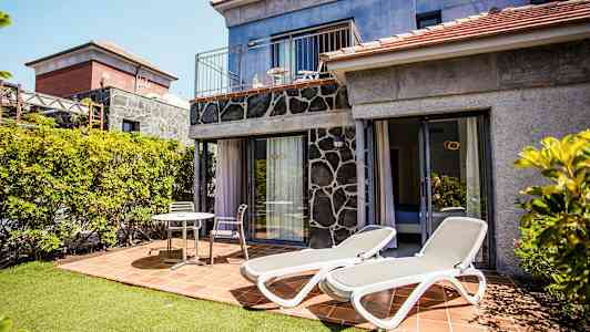 Bild av en terrass med solsängar och sittmöbler vid ett hus. (AI-genererad text)