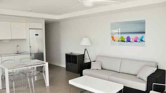 Modernt inrett vardagsrum med soffa, soffbord, matbord och kök. (AI-genererad text)