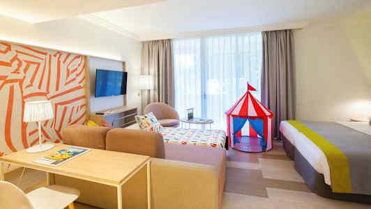 Ett hotellrum med en färgglad cirkustältleksak bredvid sängen. (AI-genererad text)