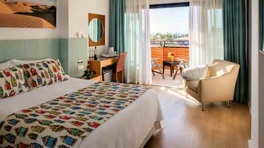 Hotellrum med dubbelsäng, sittgrupp och en balkong med utsikt. (AI-genererad text)