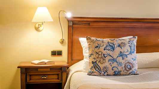 Säng med trästrukturer, prydnadskudde och bok på nattduksbord. (AI-genererad text)