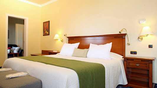 Ett hotellrum med en bred säng, grönt överkast och träinredning. (AI-genererad text)