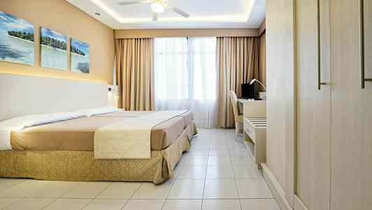 Ett hotellrum med en dubbelsäng, ett skrivbord och en takfläkt. (AI-genererad text)