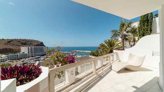 Utsikt från en solterrass över havet och en hamn. (AI-genererad text)