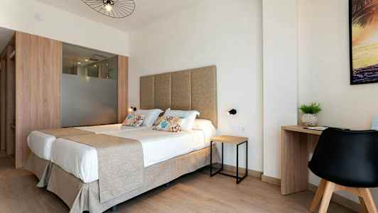 Ett ljust hotellrum med dubbelsäng och skrivbord. (AI-genererad text)