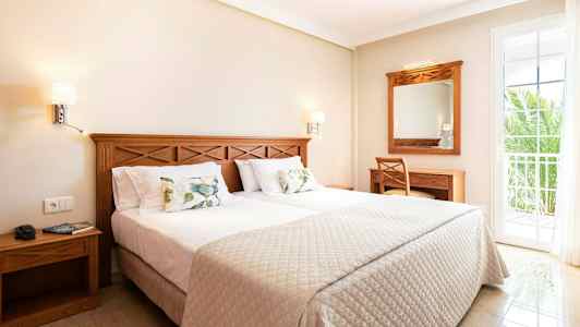 Ett hotellrum med en dubbelsäng, träinredning och en balkongdörr. (AI-genererad text)