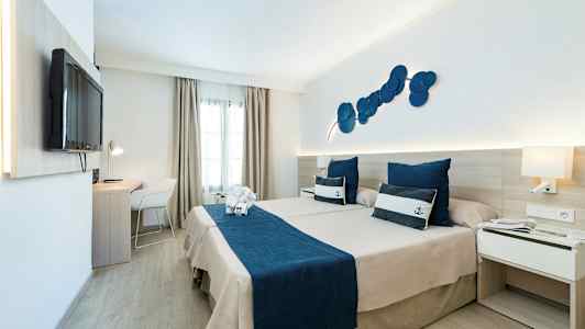 Hotellrum med två sängar och marin-tema, blå sängkläder och prydnadskuddar. (AI-genererad text)