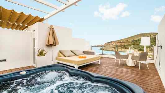 En terrass med bubbelpool, liggande möbler och utsikt över havet och landskapet. (AI-genererad text)