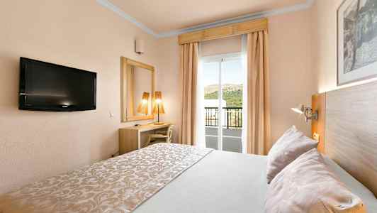 Ett hotellrum med dubbelbädd, TV, skrivbord, spegel och en balkong med utsikt. (AI-genererad text)