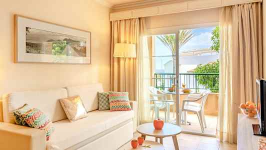 Interiör av ljust vardagsrum med soffa, bord och öppning mot terrass. (AI-genererad text)