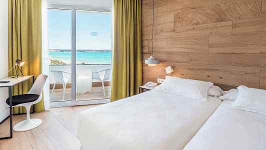 Hotellrum med två sängar, skrivbord och balkong med utsikt över havet. (AI-genererad text)