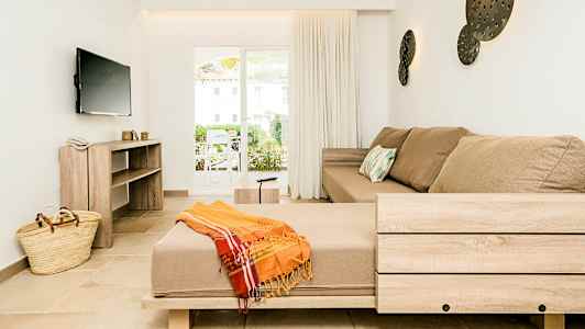 Inredningen i ett ljust vardagsrum med en beige soffa och en bred fönsterdörr. (AI-genererad text)