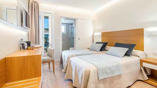 Ett hotellrum med två enkelsängar med trädetaljer, en arbetsyta och avskilt badrum. (AI-genererad text)